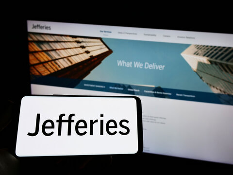 Stuttgart, Germany - 03-30-2022: Person holding mobile phone with logo of American company Jefferies Financial Group Inc on screen in front of web page. Focus on phone display.