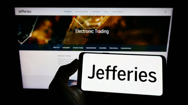 Stuttgart, Germany - 03-30-2022: Person holding cellphone with logo of US company Jefferies Financial Group Inc on screen in front of business webpage. Focus on phone display.