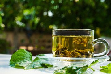 Glass cup of mulberry leaf tea on white table background.