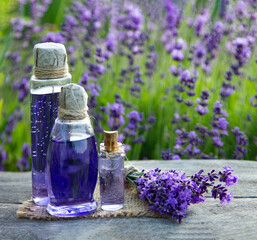 Essential oil bottle and lavender flowers field