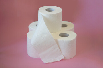 Rolls of white toilet paper on pink background