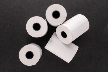 Several rolls of paper tape for a cash register on a slate stone, macro, top view.