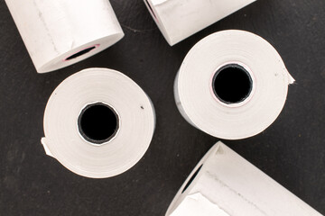 Several rolls of paper tape for a cash register on a slate stone, macro, top view.