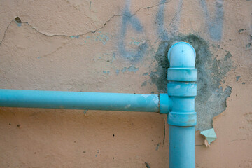 Old blue pipe on broken cement wall background