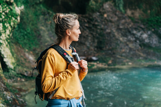 Active female tourist with a backpack in a mountainous area near a stream.