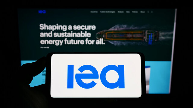 Stuttgart, Germany - 03-05-2022: Person holding mobile phone with logo of organisation International Energy Agency (IEA) on screen in front of web page. Focus on phone display.