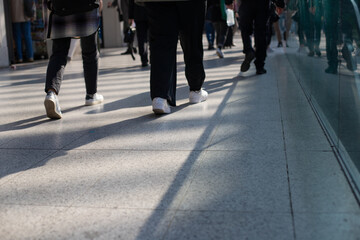 foule qui se déplace dans le même sens dans un centre commercial. On ne voit que le mouvement des jambes. 