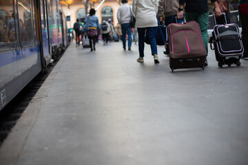 Foule de gens qui marchent dans le même sens sur le quai d'une gare à côté d'un train pour un départ en vacances ou bien pour aller au travail