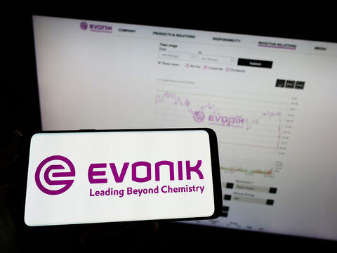 Stuttgart, Germany - 03-06-2022: Person holding mobile phone with logo of German chemicals company Evonik Industries AG on screen in front of web page. Focus on phone display.