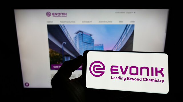 Stuttgart, Germany - 03-06-2022: Person holding smartphone with logo of German chemicals company Evonik Industries AG on screen in front of website. Focus on phone display.