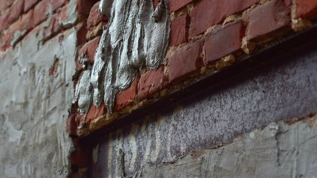 A bricklayer puts plaster on a brick wall. Plastering cement at wall for renovation house. Selective focus. Putty brick wall background. Plasterer smoothing plaster on wall.