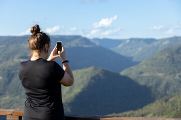 Female tourist taking photos at Parada da Torre Viewpoint, Cai River Valley, Nova Petropolis, Rio Grande do Sul highlands, Brazil - obrazy, fototapety, plakaty
