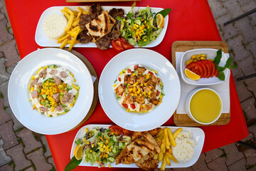 Top view of table scene with assorted take out or delivery foods. Meat and chicken doner kebab sandwich, wrap and on the plate with vegetables and sauce, including fries and pickles.