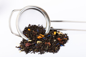 Black tea with brewing strainer isolated on white background. Dry tea leaves in a heap on a white...