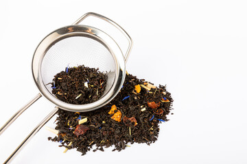 Black tea with brewing strainer isolated on white background. Dry tea leaves in a heap on a white background.