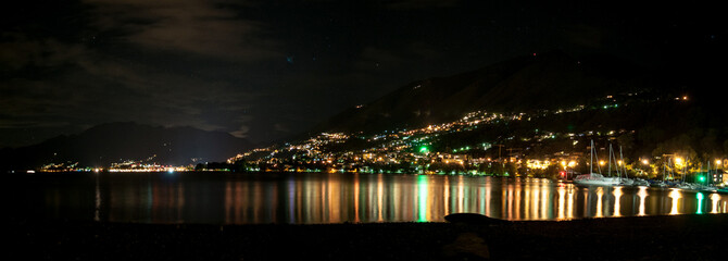 Naklejka premium Lake Locarno in Switzerland at night. The enlightened city is reflected on the water surface.