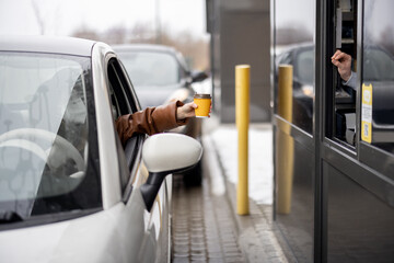 Driver takes coffee to go at the point of issuing orders on the go. Fast food and ordering during...