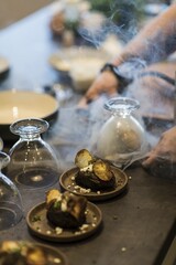 Preparing dinner. Potatoes in ashes, cream, truffles, chives, plate. Table, close-up, dining, background, lighting, people. Beautiful surroundings, adventure restaurant.