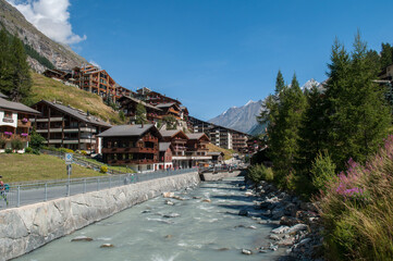 Zermatt village, Switzerland - classic wooden houses on a hill in the Swiss Alps with a river embankment