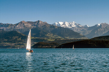 A lake in Switzerland surrounded by high mountains. Boats and sailboats sail across the lake.