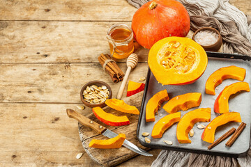 Traditional Autumn wooden background with Hokkaido pumpkin, honey, and spices ready for baking