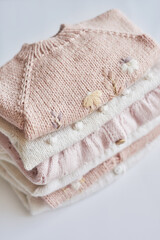 Stack of knitted clothes. Baby clothes. Needlework, hobby, knitting, handwork.