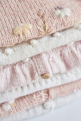 Stack of knitted clothes. Baby clothes. Needlework, hobby, knitting, handwork.