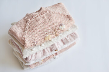 Stack of knitted clothes. Baby clothes. Needlework, hobby, knitting, handwork.