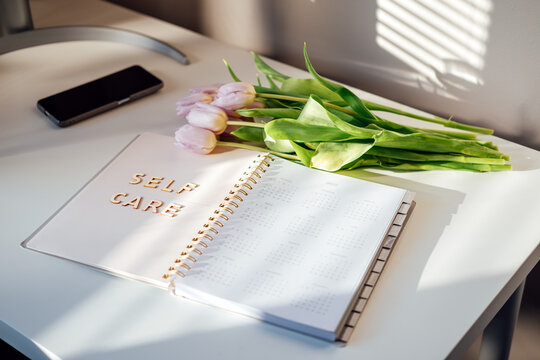 Self Care, wellbeing concept with open notebook, Self care word, tulip flowers on white table. Take care of yourself, Beauty, self care routine
