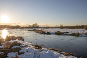 March sunny evening by the river. Blue sky over the horizon. A picturesque landscape, early spring,...