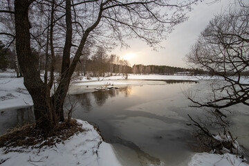 Spring landscape with a river. Snow melts in March. Evening in early spring.