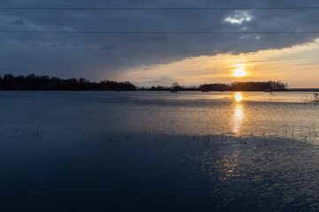 Fototapeta na wymiar Dramatic landscape, sunset over a flooded river. Flood in early spring.