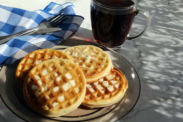Waffles with butter and syrup and coffee for brunch.