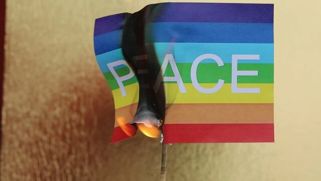 Flag with the text PEACE burning with the golden background symbolizing war and destruction