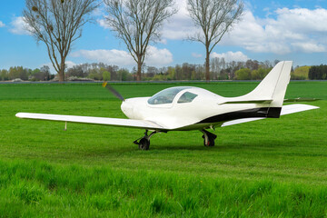 Fototapeta na wymiar A bright white plane ready to take off at a grassy airport.