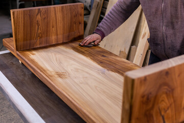Carpenter coating a wooden table with protective flaxseed oil