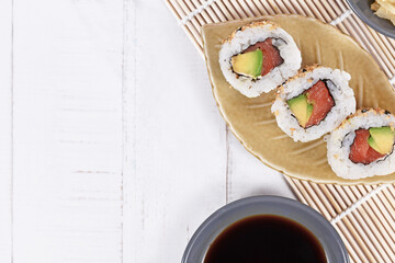 Fototapeta na wymiar Sushi inside out rolls with salmon, avocado and sesame on small leaf shaped plate