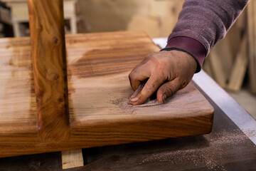 Carpenter coating a wooden table with protective flaxseed oil