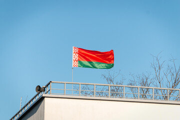 Flag of Belarus. This is the official state symbol of Belarus. Approved June 7, 1995. Belarusian red-green flag on a building against a blue sky.
