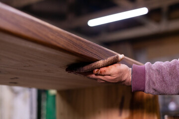 Closeup of carpenter coating a wooden table with protective flaxseed oil