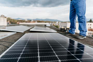 Close-up on the legs of a man standing by solar panels on the roof of a house Alternative energy....