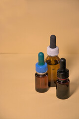 Glass bottles with droppers inside for medicine, health care, skin care products. Brown bottles in yellowish background.