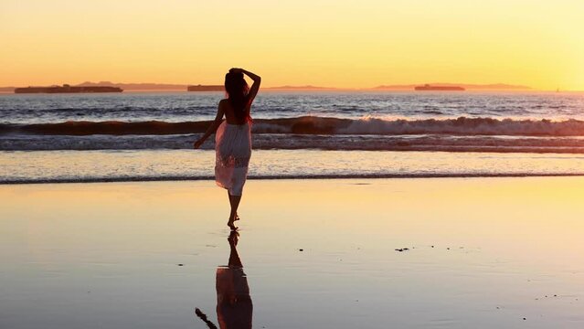 Pretty Asian woman enjoys a walk on the beach at sunset. Slow Motion.