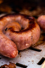 Close up shot of rolled up sausages on skewer placed over barbeque
