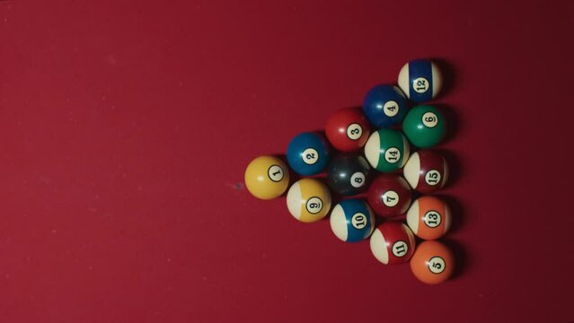 Top view on young female, woman hands pick up triangle form pyramid from 15 colorful pool balls on red american classic table on beginning of weekend hobby game with friends or local sport competition