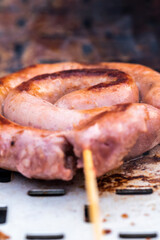 Close up shot of rolled up sausages on skewer placed over barbeque