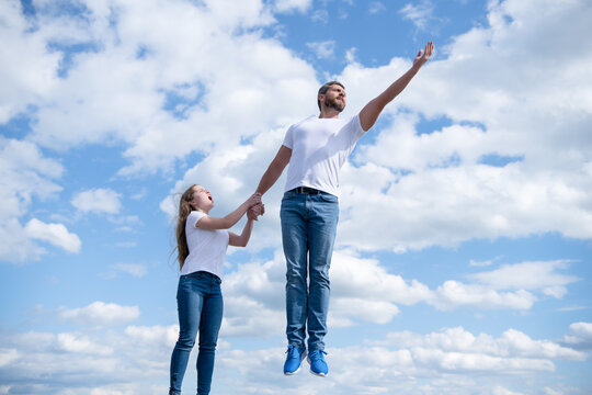 daughter hold her daddy jumping in sky