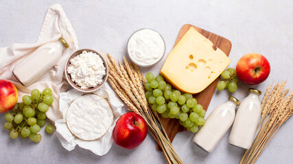 Shavuot flat lay with dairy products, first fruits and wheat on light gray background