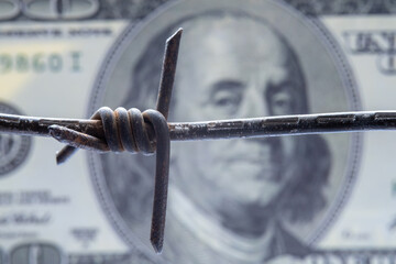 Economic warfare, sanctions and embargo busting concept. US Dollar money and barbed wire. Selective...