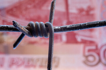 The concept of war, sanctions and the devaluation of the ruble. Close up of dirty barbed wire...